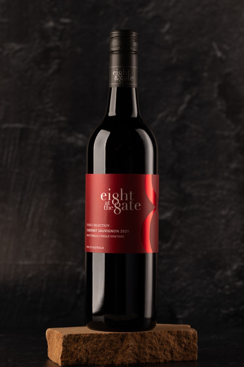 Bottle of red wine in a dark moody setting on a wooden board